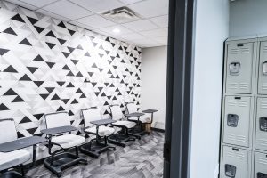 Geometric triangle black and white wallpaper on left hand wall. Moveable desks line left wall.